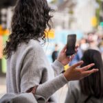 woman in gray sweater holding smartphone