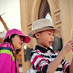 girl watching behind boy holding smartphone